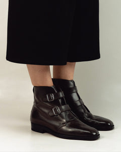 Woman wearing double monk strap boots styled with tailored outerwear for a modern, refined look